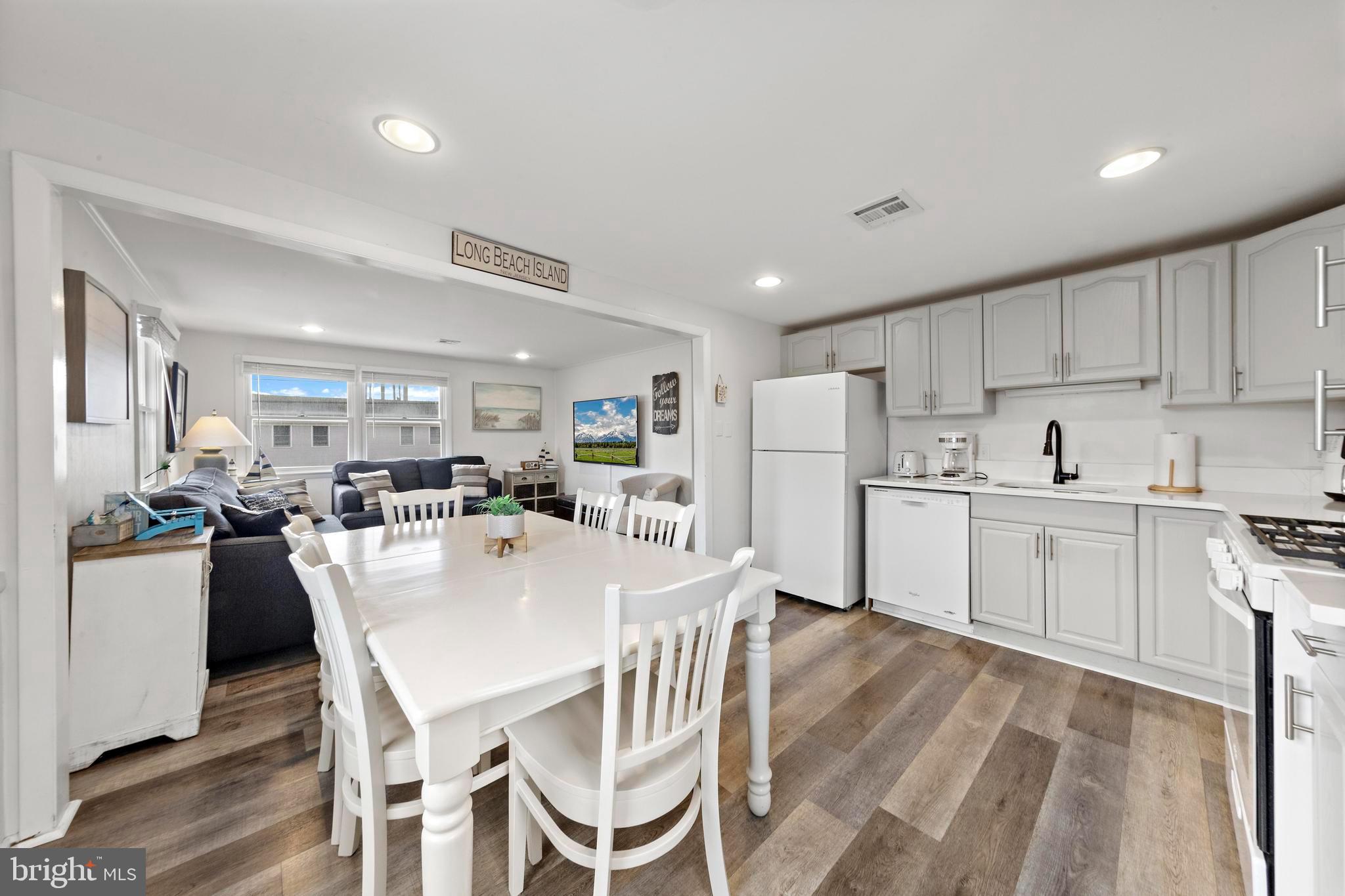 13 Joan Road, Unit 2 Long Beach Township, NJ 08008 - Photo 6 of 64 a kitchen with a dining table chairs wooden floor cabinets and appliances