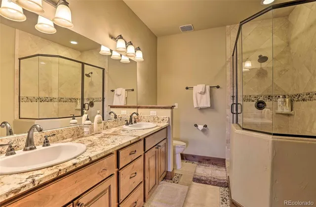 a bathroom with a granite countertop sink mirror and a shower