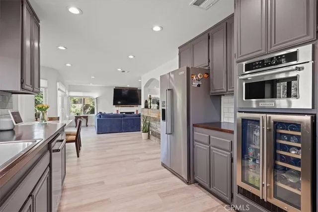 a kitchen with stainless steel appliances kitchen island granite countertop a refrigerator oven a sink dishwasher and wooden cabinets with wooden floor