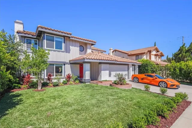 a front view of a house with garden and trees