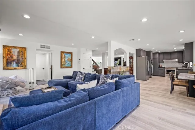 a living room with furniture kitchen view and a wooden floor