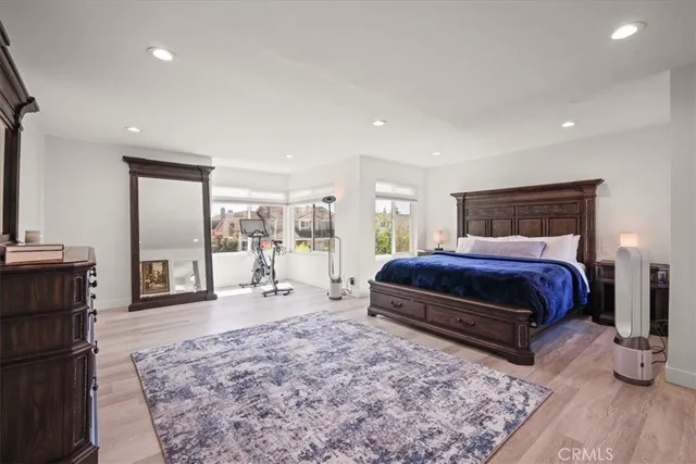 a bedroom with a bed and large mirror with wooden floor