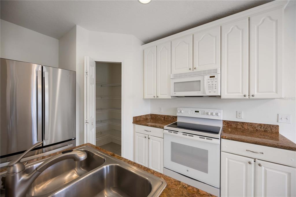 14980 Skip Jack Loop Lakewood Ranch, FL 34202 - Photo 12 of 39 a kitchen with granite countertop white cabinets and refrigerator