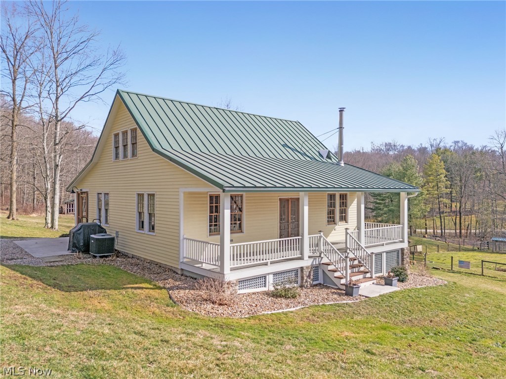 2210 Scroll Road Southwest Carrollton, OH 44615 - Photo 2 of 48 Back of house featuring covered porch, a standing seam roof, and a yard