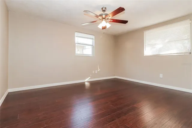 a view of an empty room with a window and wooden floor