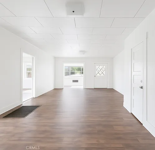 a view of an empty room with window and wooden floor