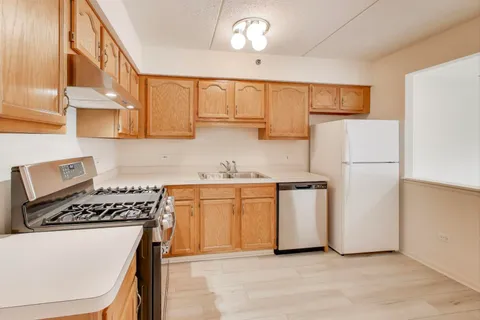 a kitchen with a refrigerator a stove a sink and white cabinets with wooden floor