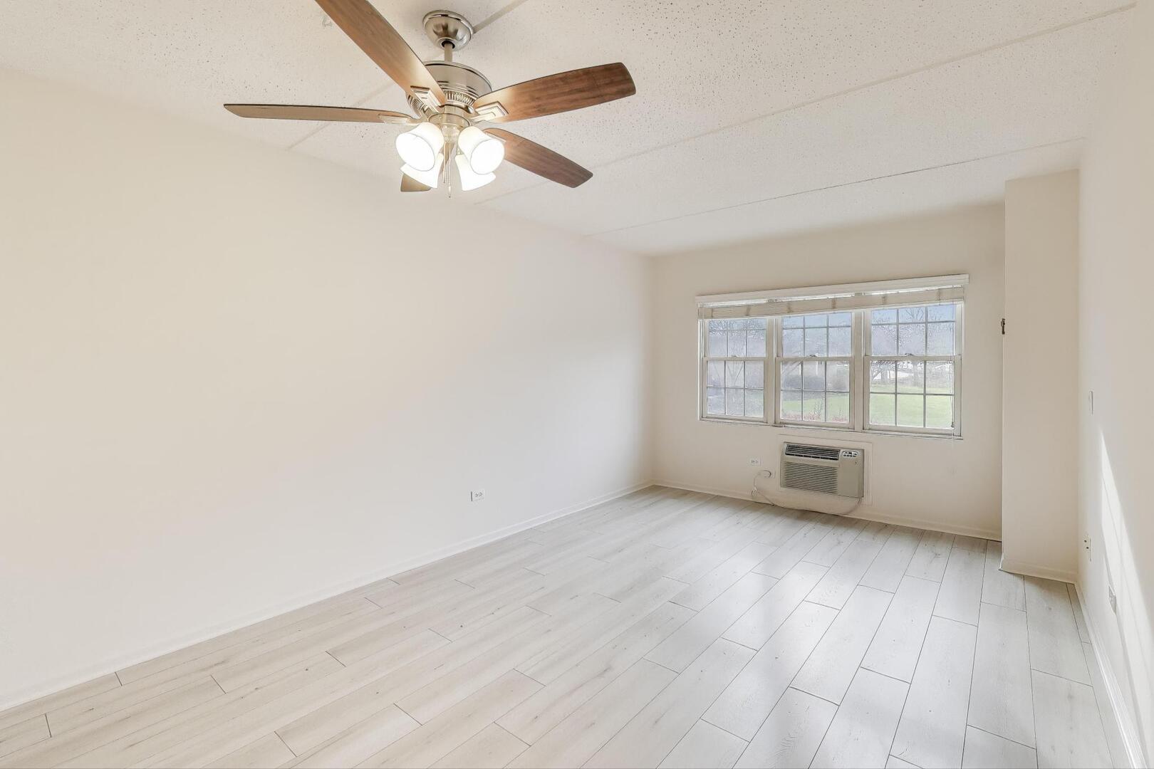 1220 Depot Street, Unit 109 Glenview, IL 60025 - Photo 7 of 35 an empty room with wooden floor fan and windows