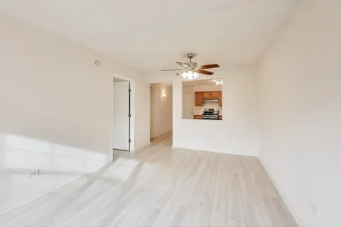 an empty room with wooden floor and kitchen view