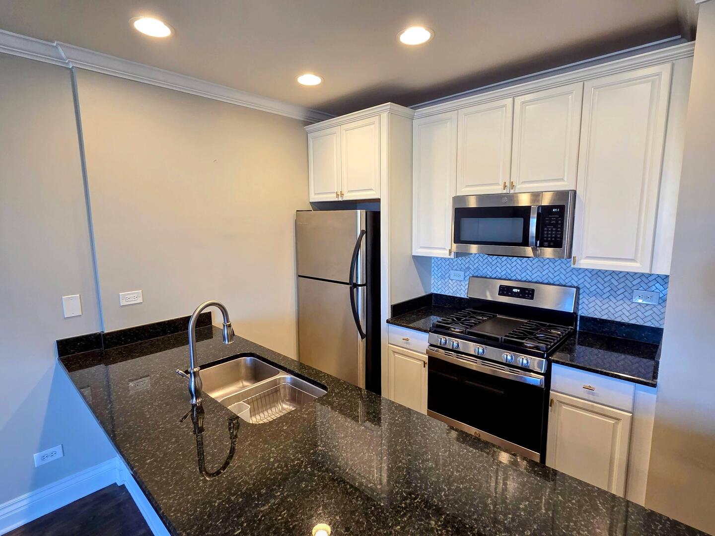 1422 North Noble Street, Unit 2S Chicago, IL 60642 - Photo 5 of 15 a kitchen with granite countertop a refrigerator stove and microwave