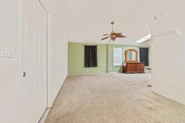 a view of an empty room with chandelier fan and fire place