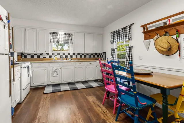 a kitchen with granite countertop a sink a stove and white cabinets
