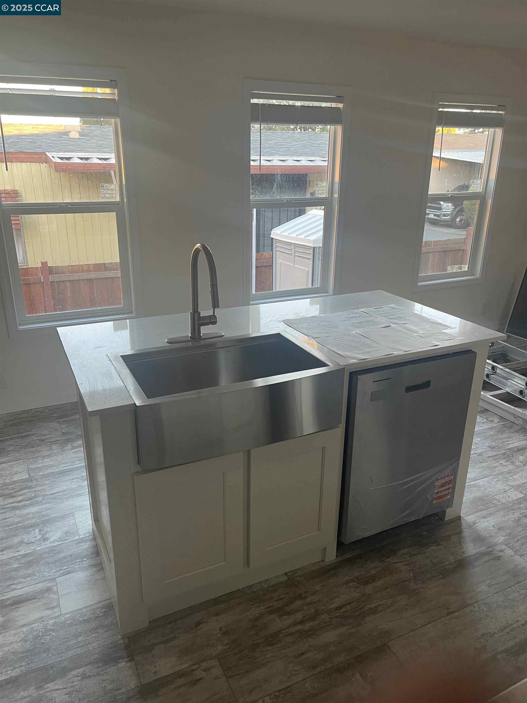 3777 Willow Pass Road, Unit 85 Bay Point, CA 94565 - Photo 3 of 7 a kitchen with kitchen island granite countertop a sink and wooden floor