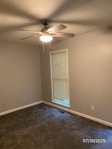 an empty room with a chandelier fan and windows