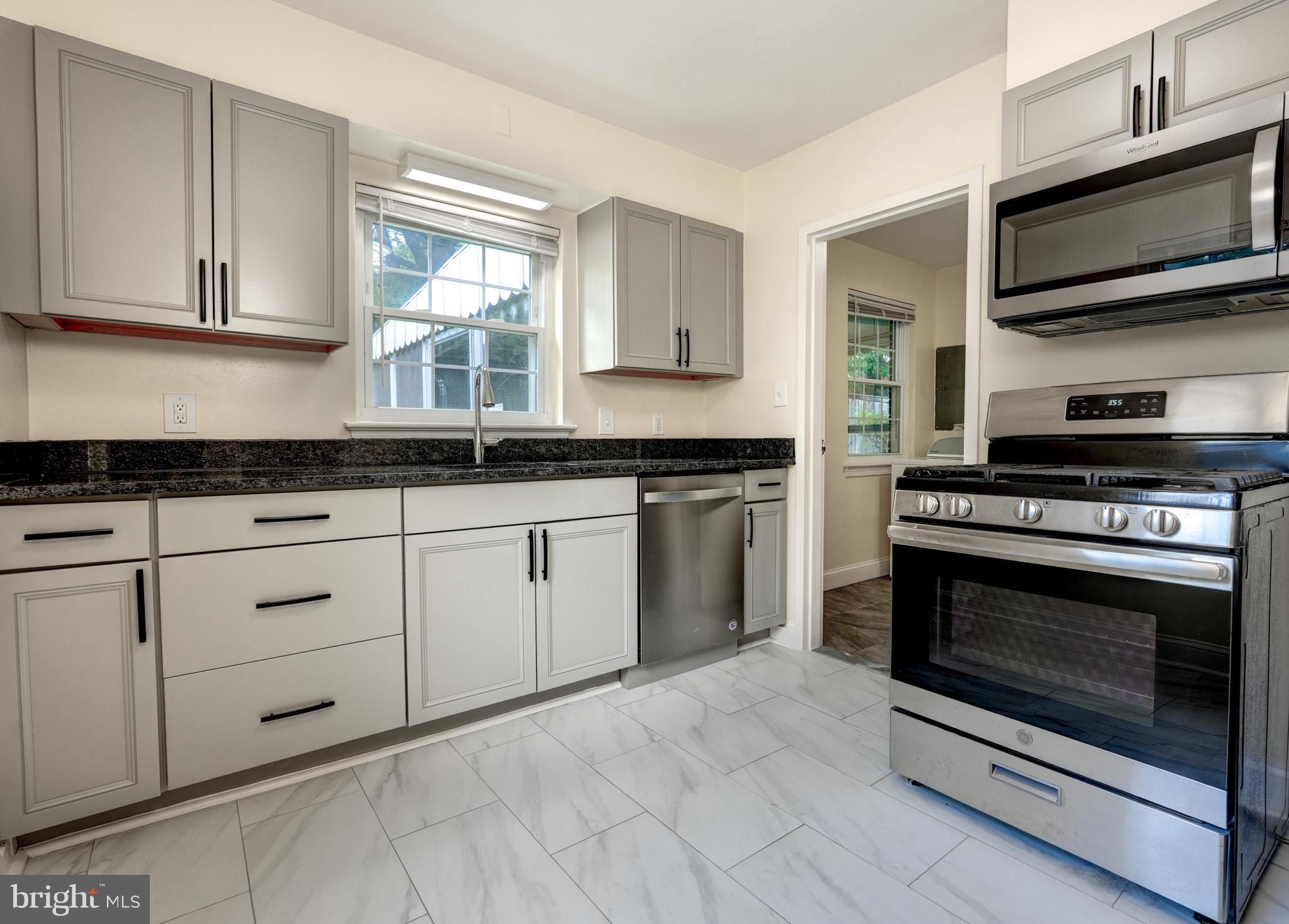 9912 Markham Street Silver Spring, MD 20901 - Photo 20 of 28 a kitchen with granite countertop white cabinets stainless steel appliances and window