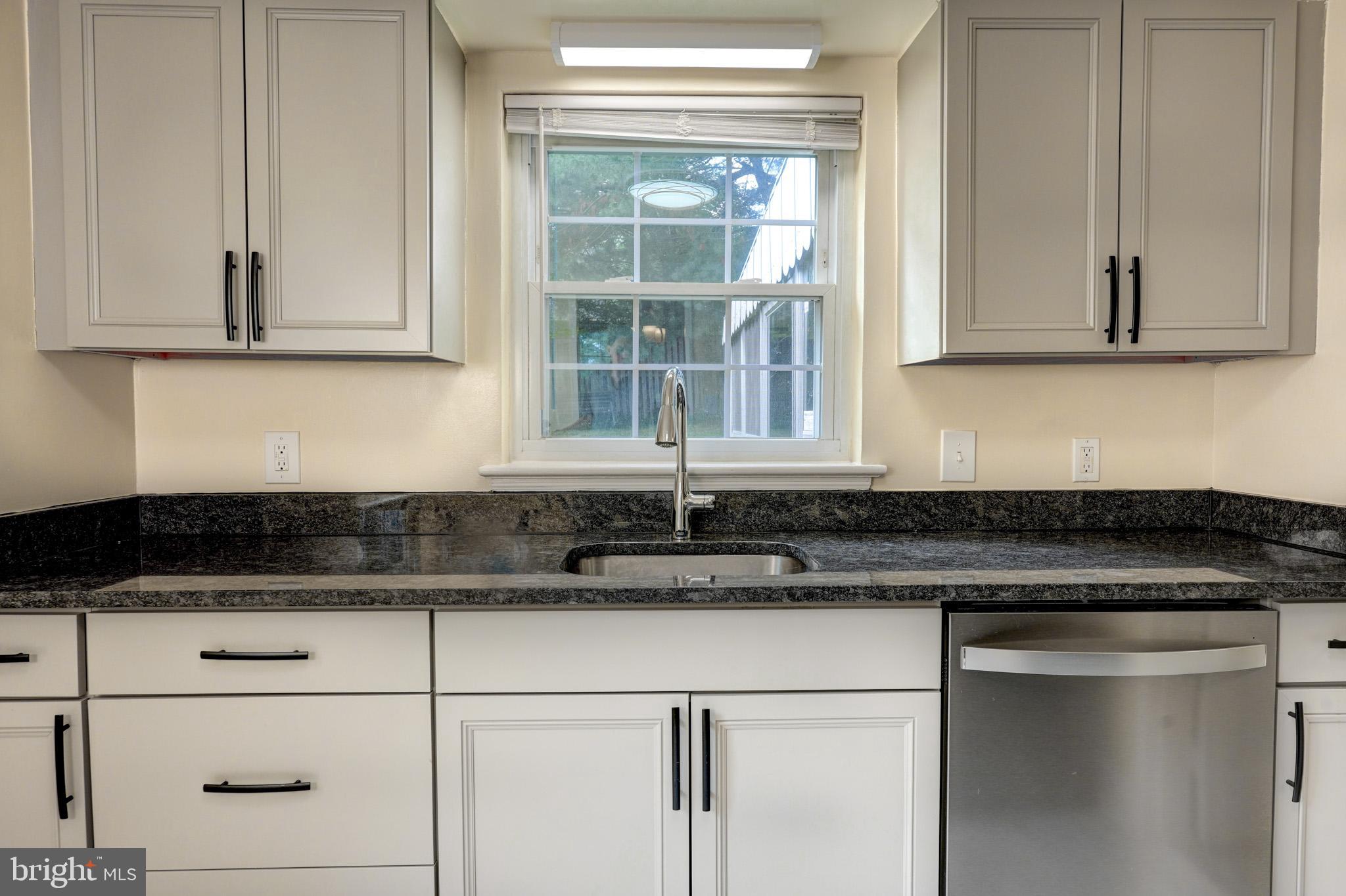 9912 Markham Street Silver Spring, MD 20901 - Photo 21 of 28 a kitchen with granite countertop white cabinets and white appliances