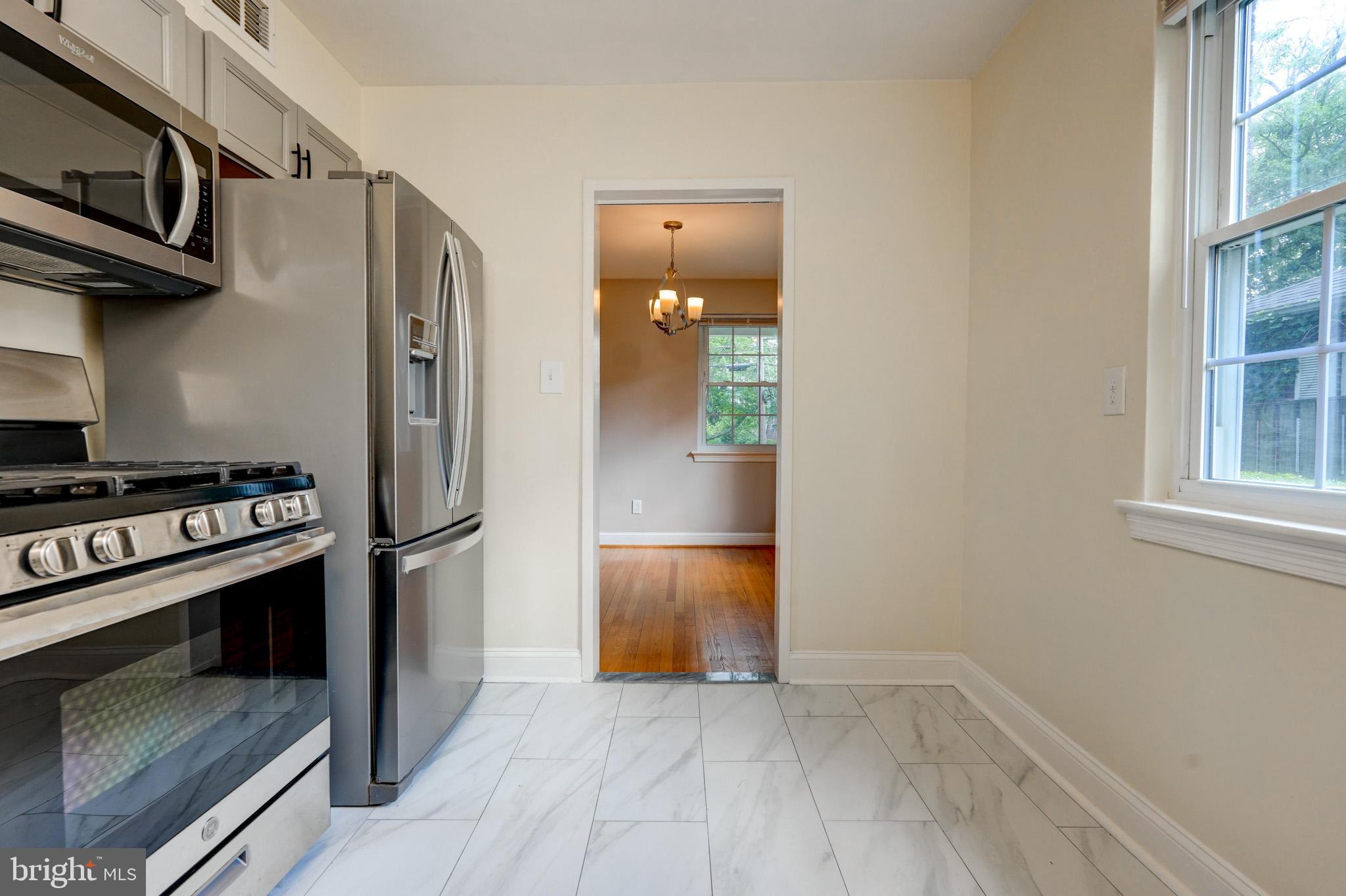 9912 Markham Street Silver Spring, MD 20901 - Photo 26 of 28 a view of a kitchen with a stove fridge and wooden floor