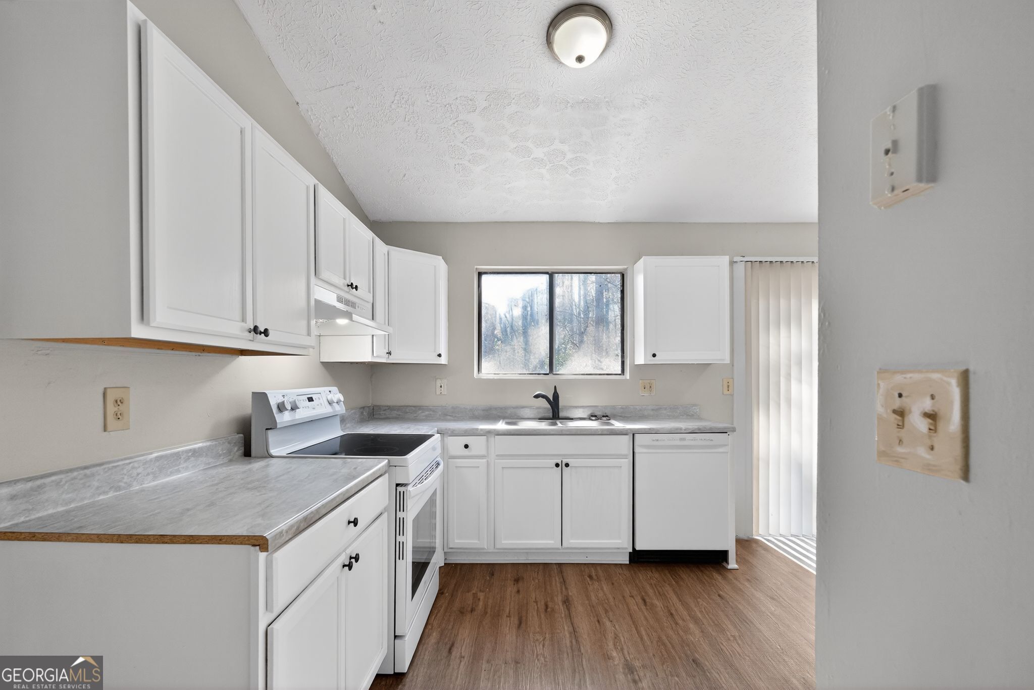5515 Rock Springs Road Lithonia, GA 30038 - Photo 11 of 34 a kitchen with a sink dishwasher a stove and white cabinets with wooden floor