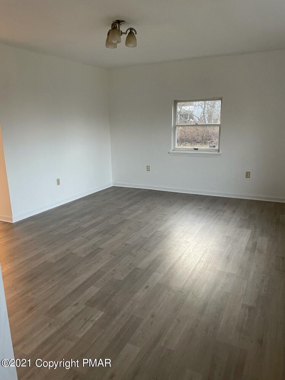 121 Ryan Road Blakeslee, PA 18610 - Photo 8 of 27 an empty room with wooden floor and windows