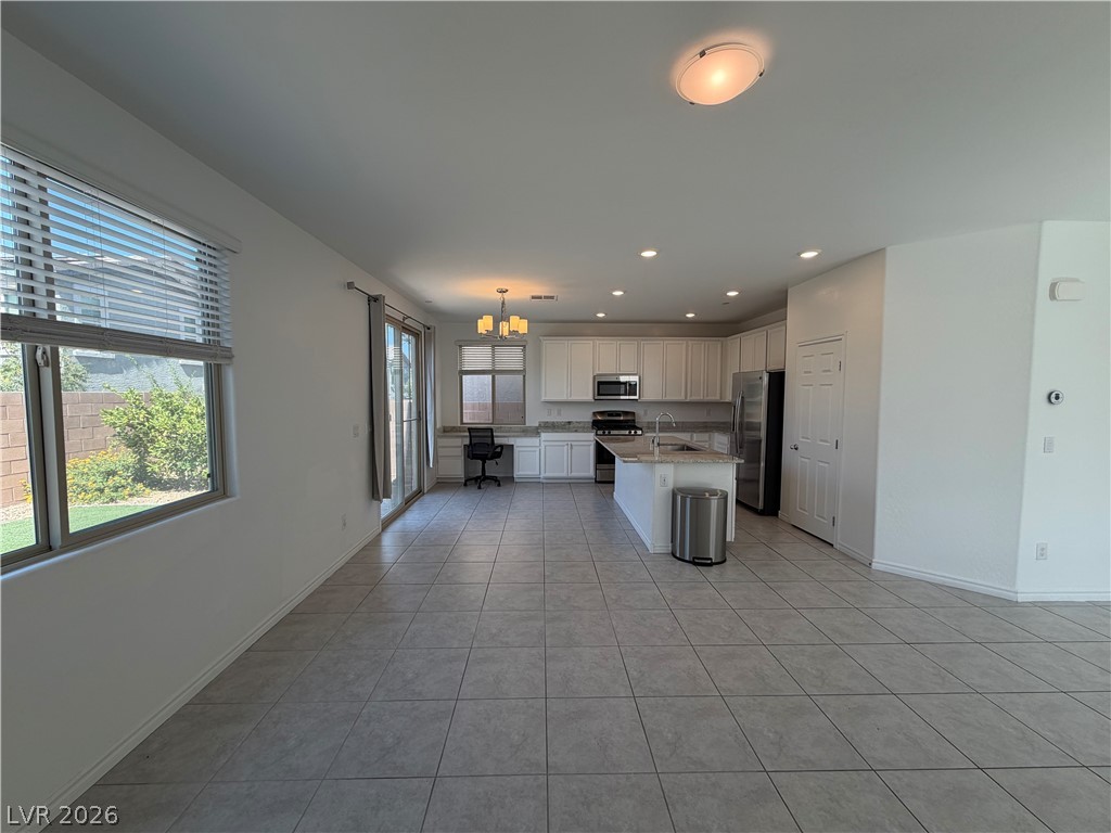 3228 Azalea Ridge Court Henderson, NV 89052 - Photo 3 of 28 An open-concept living area flows into a chef's kitchen, featuring tiled floors and abundant natural light.