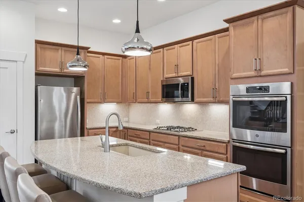 a kitchen with kitchen island granite countertop a stove and a sink with granite countertops