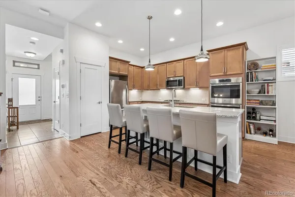 a kitchen with stainless steel appliances kitchen island granite countertop a table chairs and a refrigerator