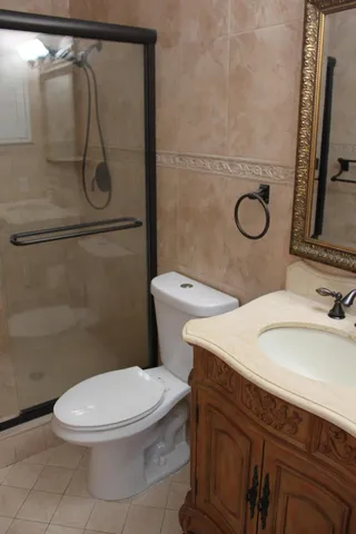 a bathroom with a granite countertop toilet sink and mirror