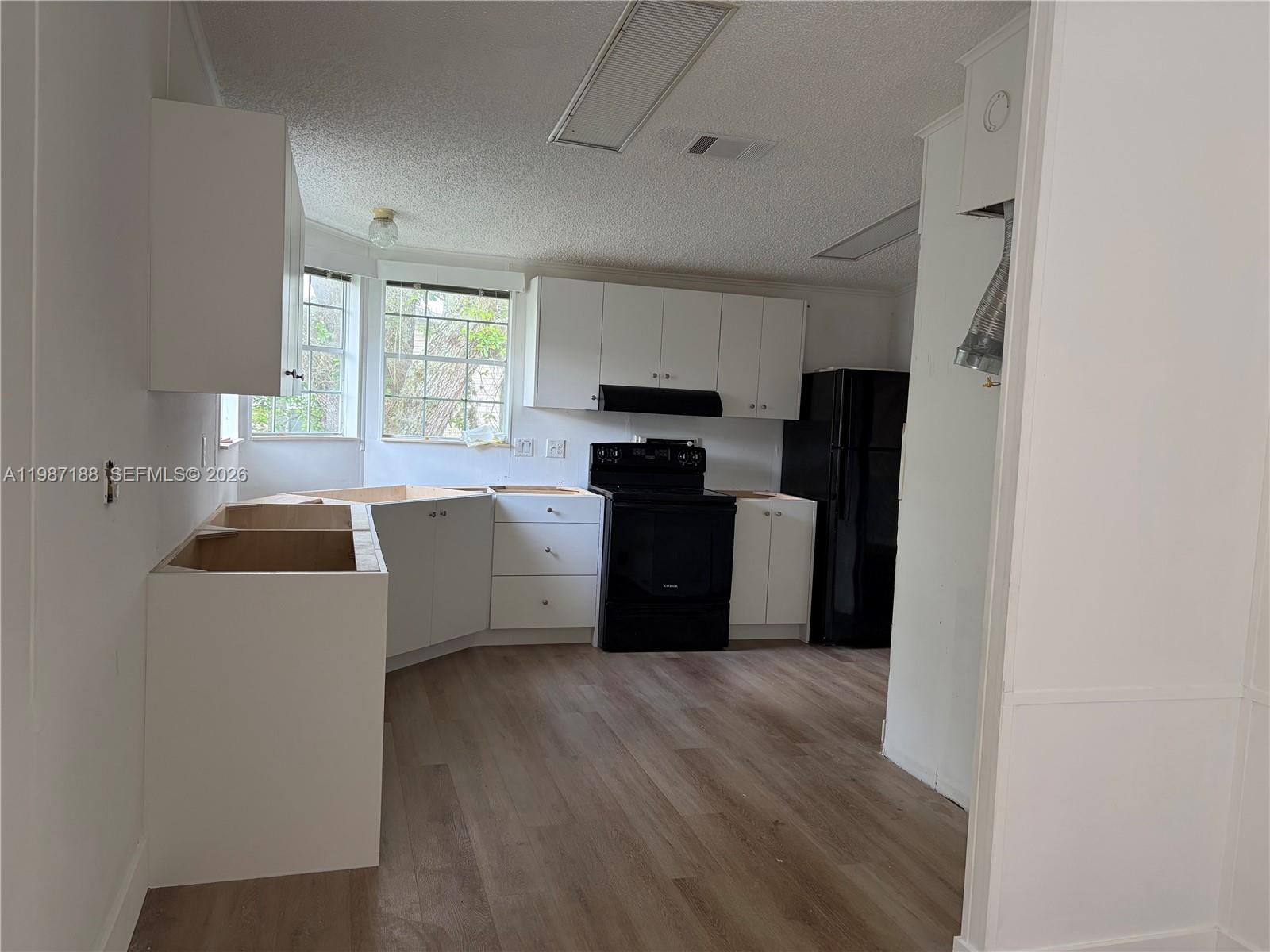 35303 Southwest 180th Avenue, Unit 391 Homestead, FL 33034 - Photo 23 of 23 a kitchen with a refrigerator a stove top oven a sink dishwasher and white cabinets with wooden floor