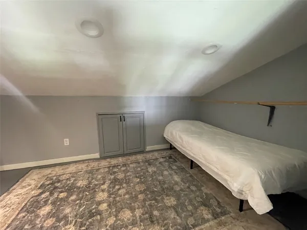 a spacious bedroom with a bed and wooden floor