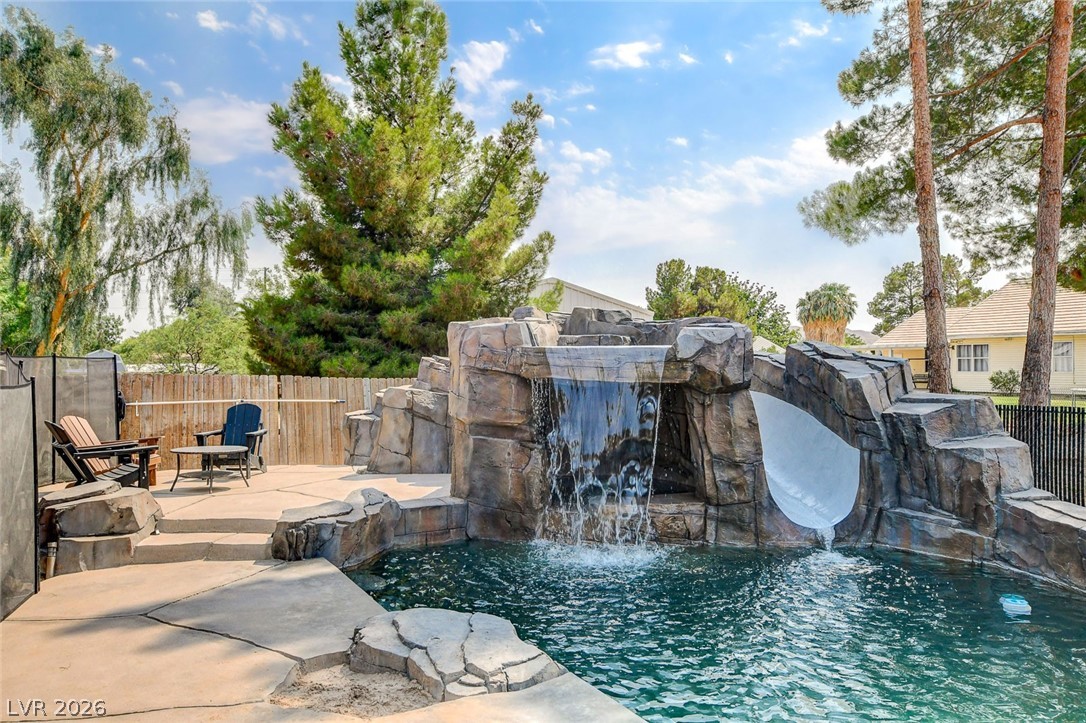 3765 Berkeley Street Logandale, NV 89021 - Photo 81 of 87 A rock waterfall cascades into a refreshing private pool, featuring an integrated waterslide and surrounding patio space.