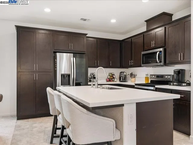 a kitchen with stainless steel appliances granite countertop a sink a stove and a refrigerator