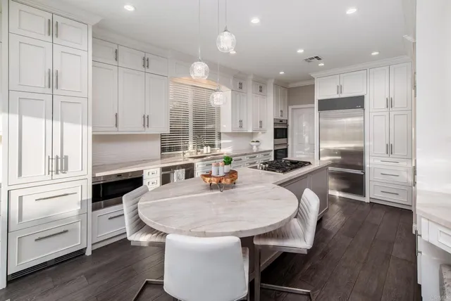 a kitchen with kitchen island a stove a sink a refrigerator and white cabinets with wooden floor