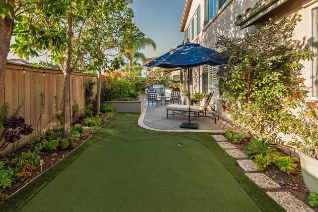 a backyard of a house with table and chairs under an umbrella