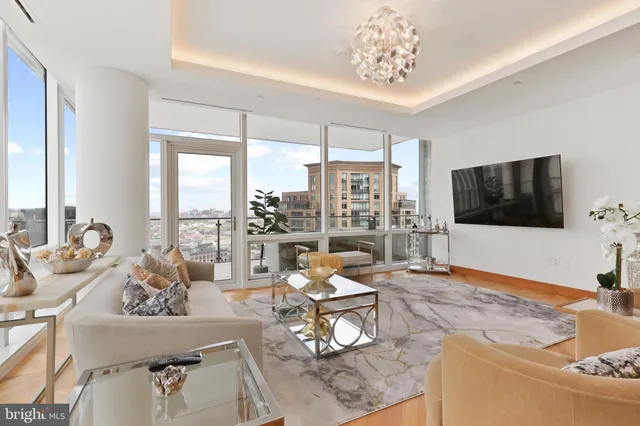 a living room with furniture a flat screen tv and a floor to ceiling window