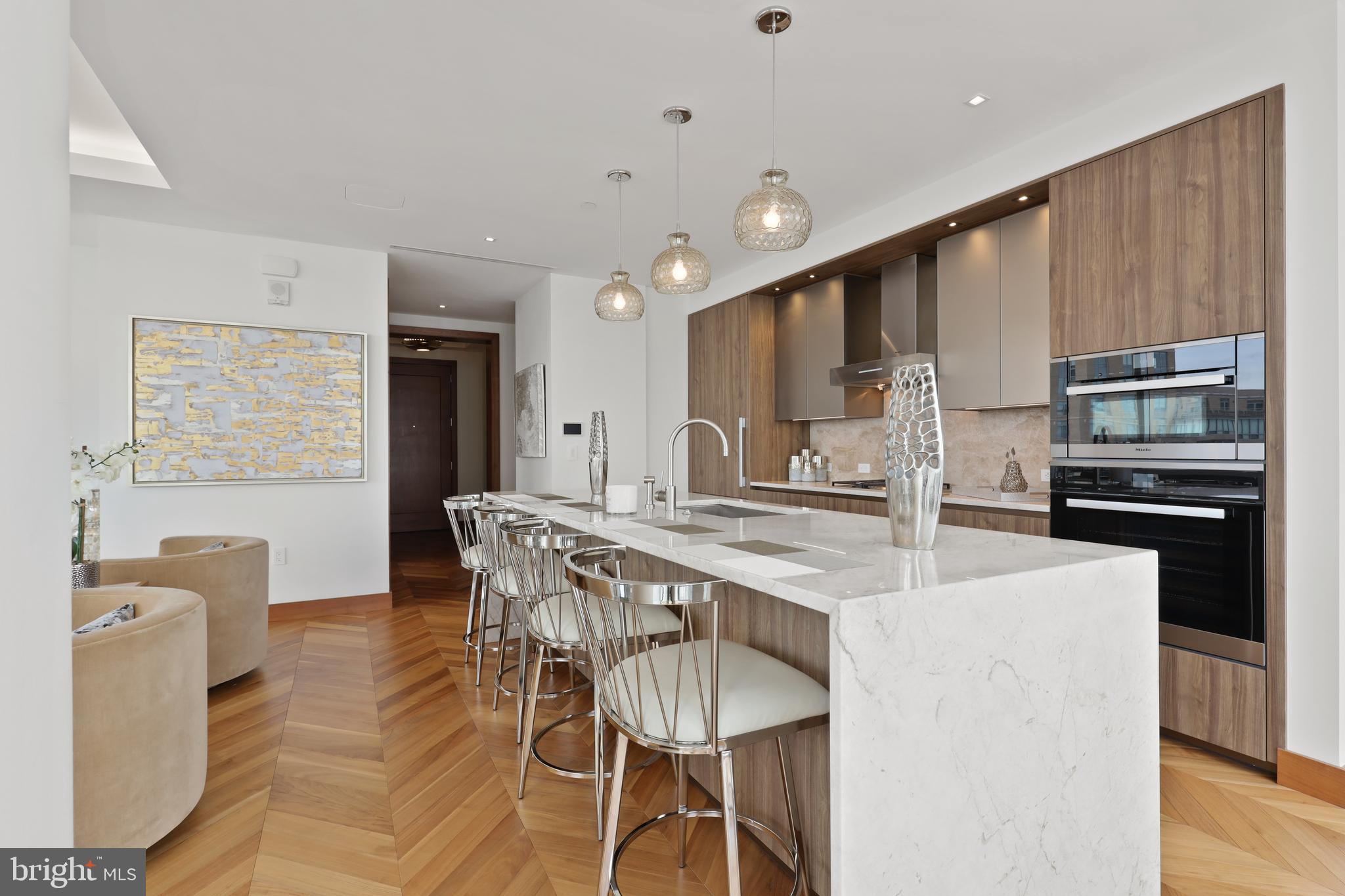 300 International Drive, Unit 2403 Baltimore, MD 21202 - Photo 9 of 36 a kitchen with stainless steel appliances kitchen island granite countertop a kitchen island and chairs in it