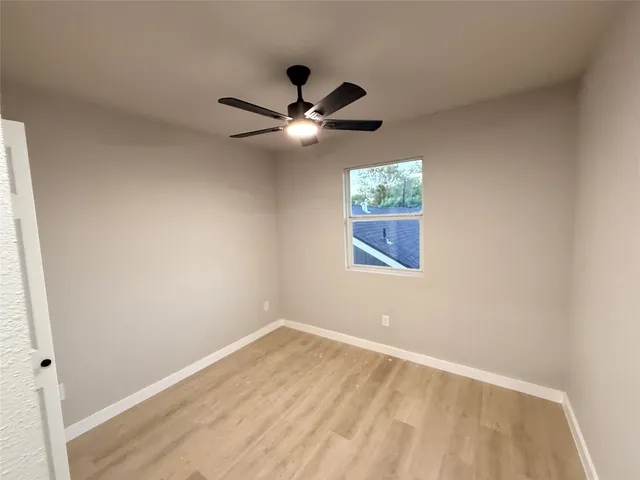 an empty room with a window and a fan