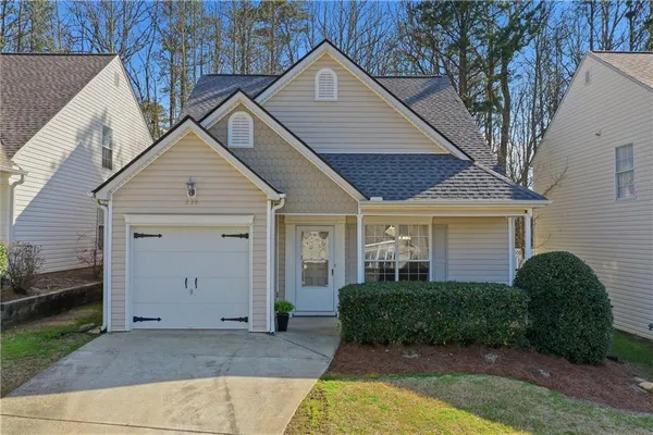a view of a house with a yard plants and large tree