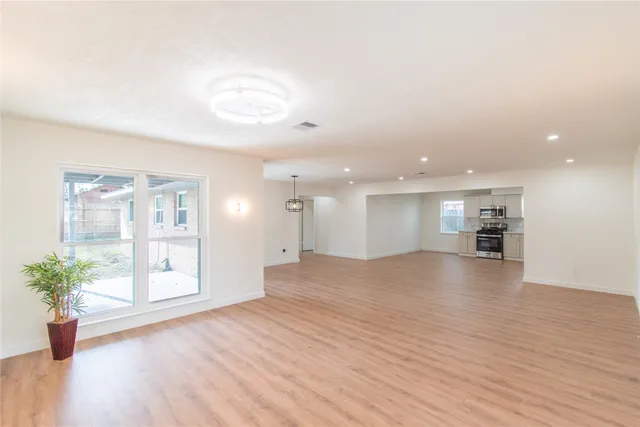an empty room with wooden floor and windows