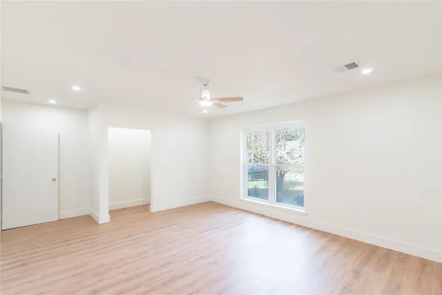 an empty room with a window and a ceiling fan