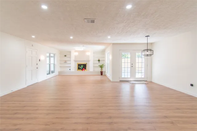 a view of an empty room with window and wooden floor