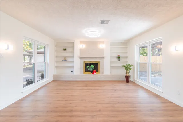 a view of an empty room with wooden floor and windows