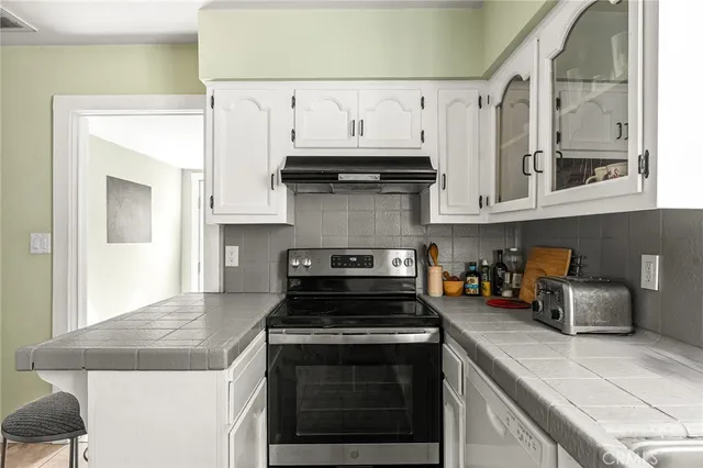 a kitchen with stainless steel appliances granite countertop a stove a sink and white cabinets