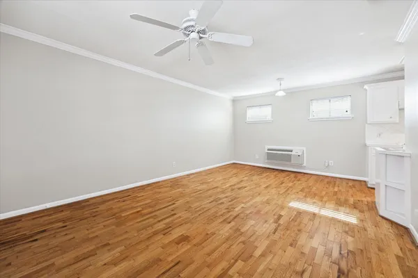 a view of empty room with wooden floor and fan