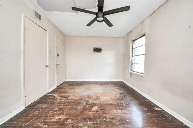 a view of empty room with wooden floor and fan