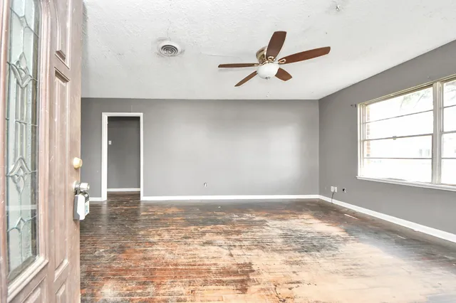 an empty room with windows and ceiling fan