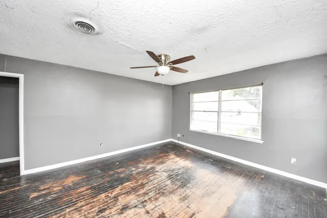 an empty room with wooden floor and ceiling fan