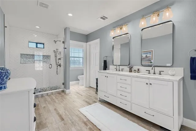 a spacious bathroom with a double vanity sink a mirror and a shower