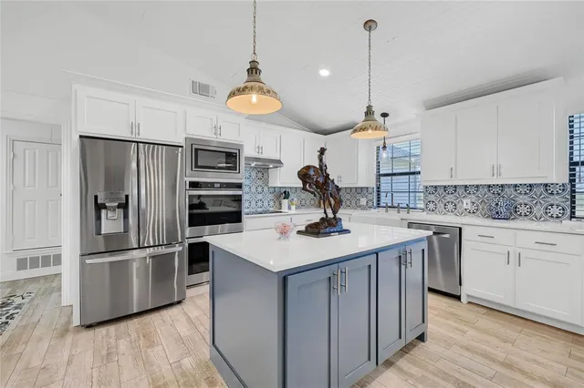 a kitchen with a sink stainless steel appliances and wooden floor