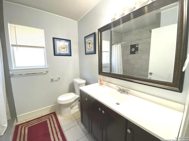 a bathroom with a sink a toilet a mirror and a window