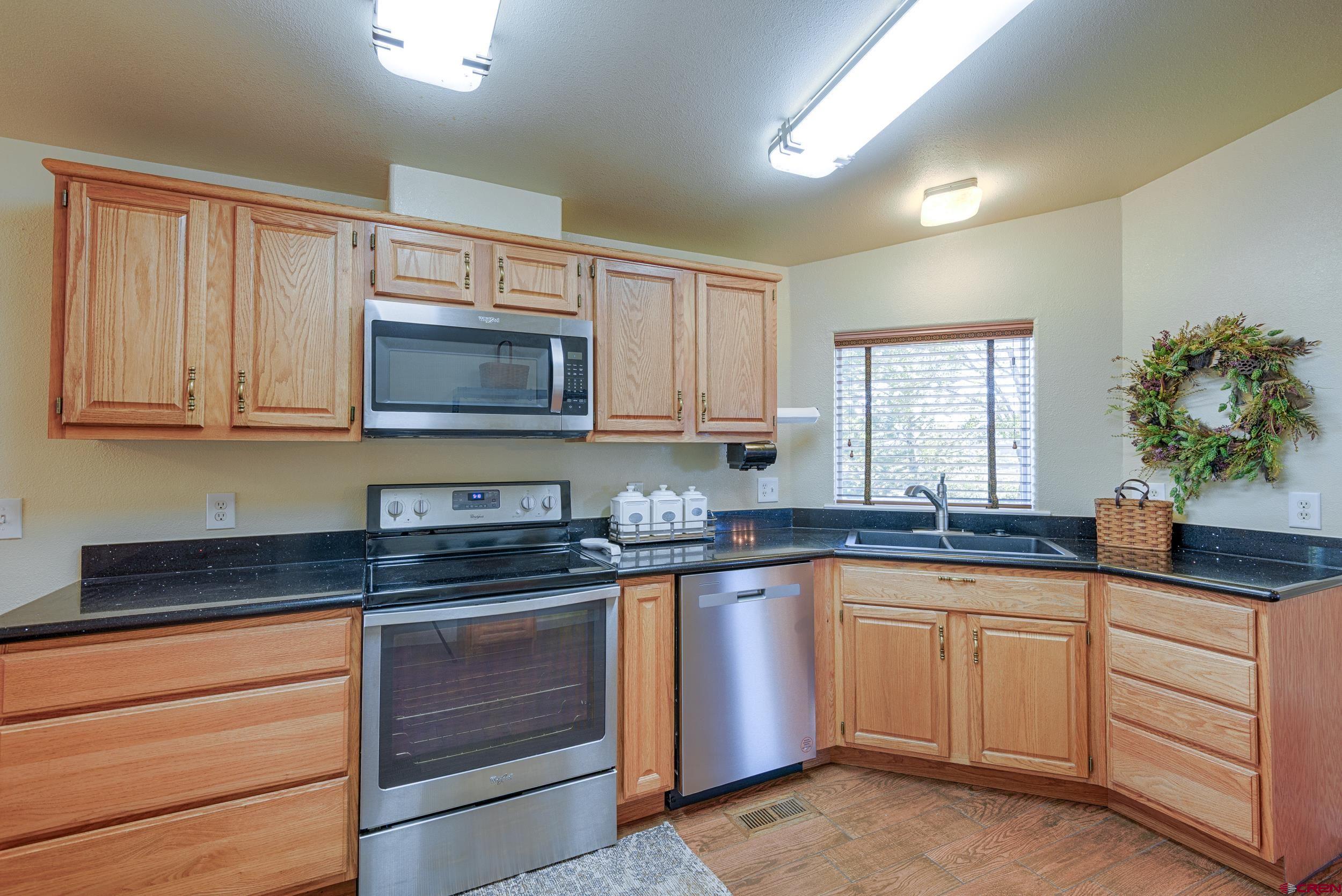 61928 Jay Jay Road Montrose, CO 81401 - Photo 8 of 36 a kitchen with granite countertop white cabinets sink and stainless steel appliances